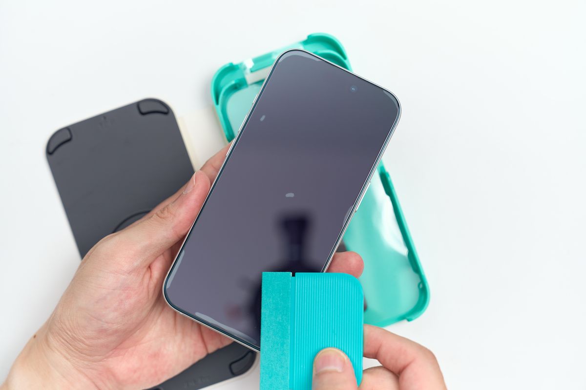 ガラスフィルムを貼ったiPhone 17の気泡をヘラで押し出している