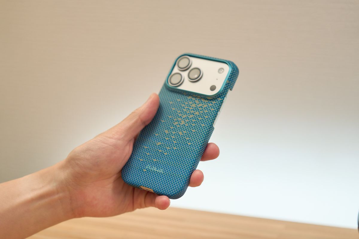 PITAKA 浮光躍金 アーティストコレクション ギフトボックス(青月夢 / Lucid Blue)のUltra-Slim Case(極薄ケース)を装着したiPhoneを手に持っている